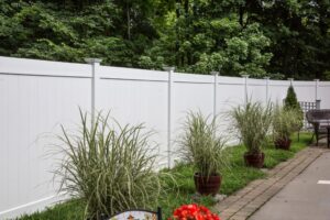 Picture of a white fence bordered by potted plants.