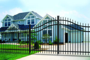An aluminum fence with an ornate gate in front of a light blue house